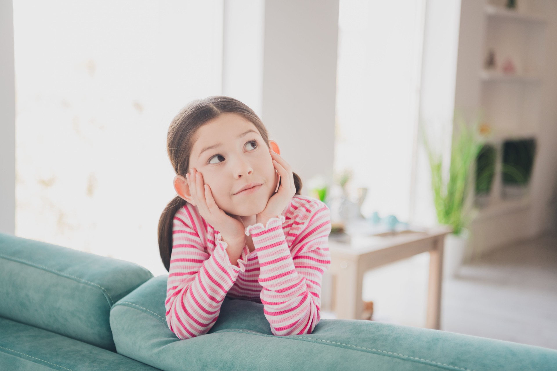 Close up photo of adorable preteen lovely funny kid little brunette girl staying at home spending holidays lying on couch isolated in her room