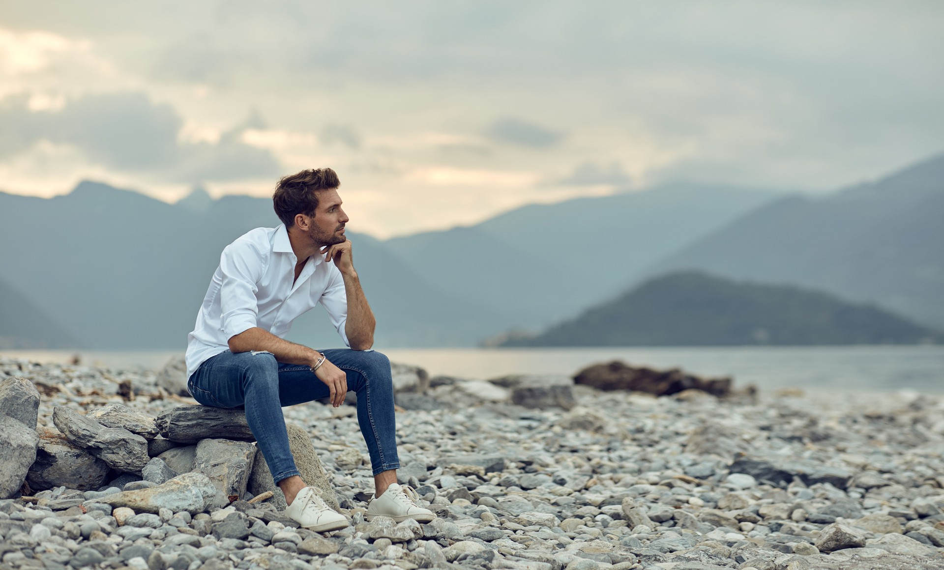 Handsome man in casual clothing relaxing on the beach