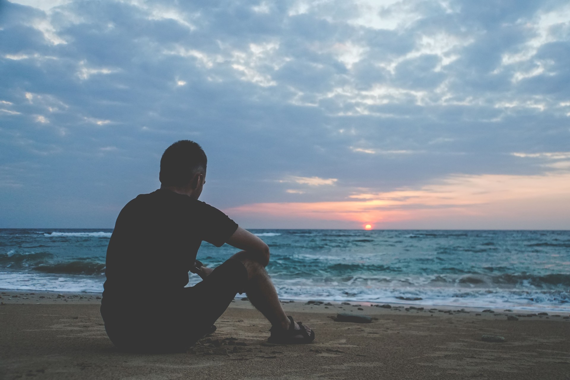 alone man looking at the sunset on a beach